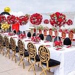 Beautiful wedding table with red and white floral arrangements and gold-accented chairs.